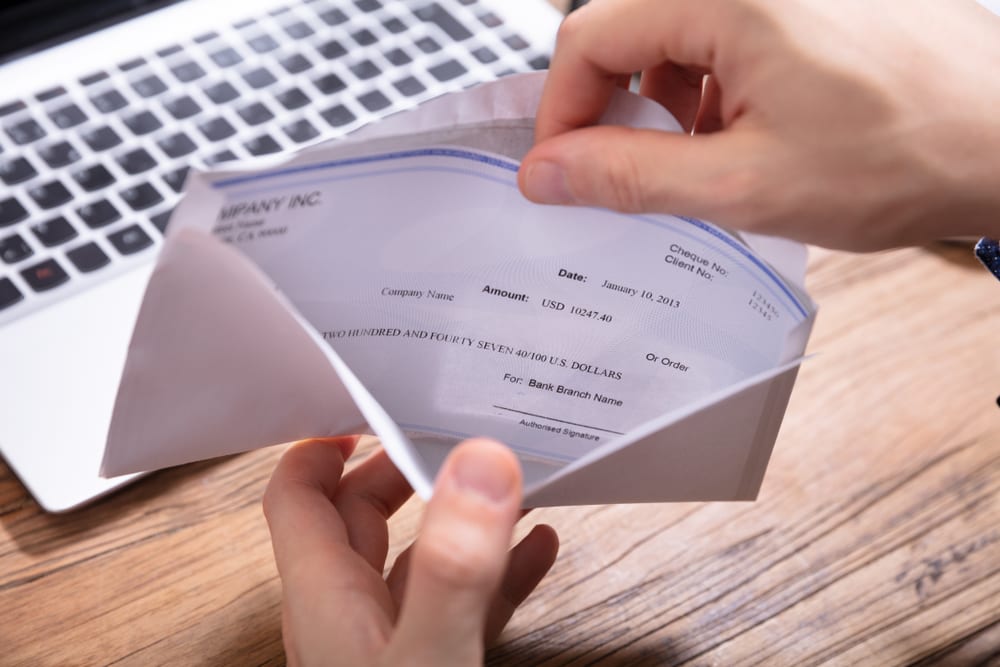 Elevated,View,Of,Person’s,Hand,Removing,Paycheck,From,The,Envelope